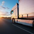Loaded European truck on motorway in beautiful sunset light. On the road transportation and cargo.