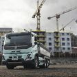 elektrischer Lkw mit Kipperaufbau vor städtischer Baustelle
