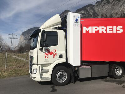 Satttelzugmaschine vor Stromleitung und Bergkulisse