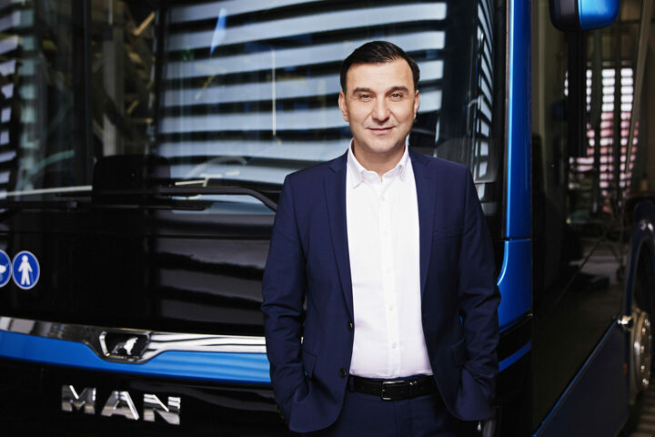 Barbaros Oktay, Head of Bus, MAN Truck & Bus SE, vor einem MAN Bus, mit Händen in den Hosentaschen