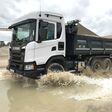 Scania-Lkw fährt durch eine Wasser-Pfütze
