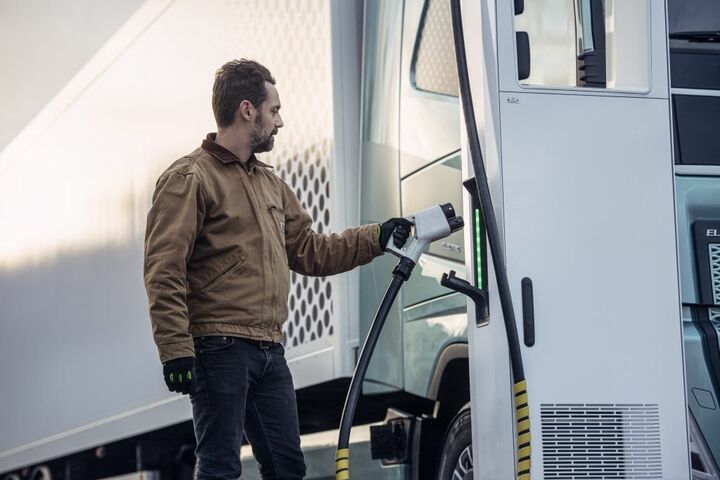 Ein Mann steckt einen Elektro-Lkw zum Laden mit Strom an
