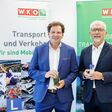 Wolfgang Böhm, Fachgruppe Transporteure in der Wirtschaftskammer Wien, und Davor Sertic, Obmann der Sparte Transport und Verkehr in der WK Wien, zeigen ein Glas mit herkömmlichen Diesel und dem farblosen HVO 100.